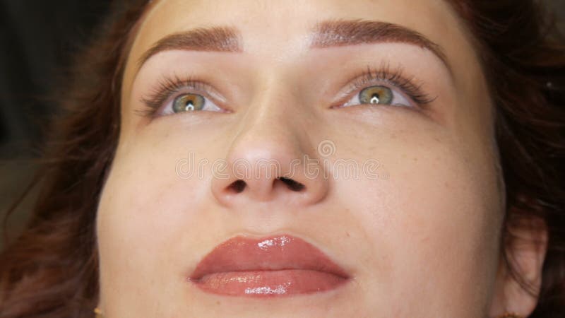 La belle jeune femme avec le maquillage permanent de la lèvre et le tatouage microblading de sourcil se retrouve avec un salon de clips vidéos