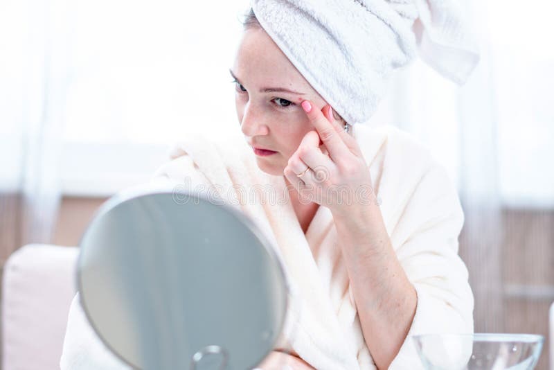 La belle jeune femme malheureuse détecte l'acné sur son visage Concept d'hygiène et d'entretenir la peau image libre de droits La belle jeune femme malheureuse détecte l'acné sur son visage Concept d'hygiène et d'entretenir la peau image libre de droits