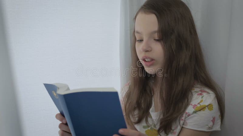 La belle petite fille apprend un poème par la fenêtre