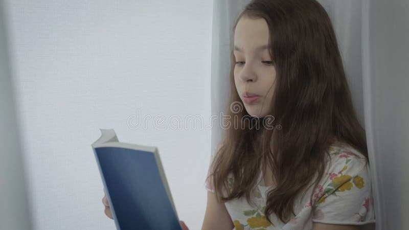 La belle petite fille apprend un poème par la fenêtre