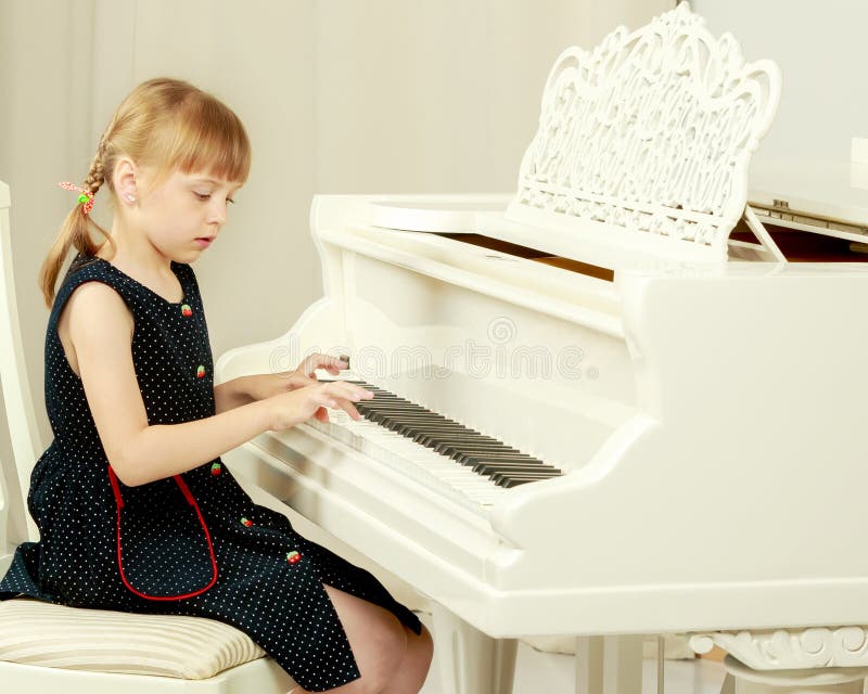 La belle petite fille joue sur un piano ? queue blanc image stock La belle petite fille joue sur un piano ? queue blanc image stock
