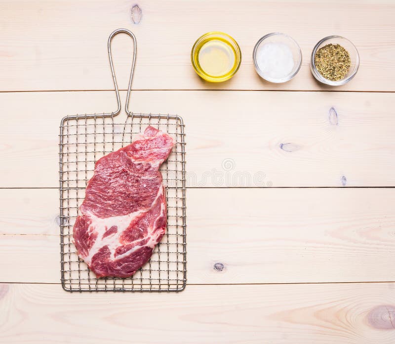 La bistecca cruda deliziosa della carne di maiale sulla griglia per grigliare, là è una serie di spezie ed olio, il testo del pos fotografie stock La bistecca cruda deliziosa della carne di maiale sulla griglia per grigliare, là è una serie di spezie ed olio, il testo del pos fotografie stock