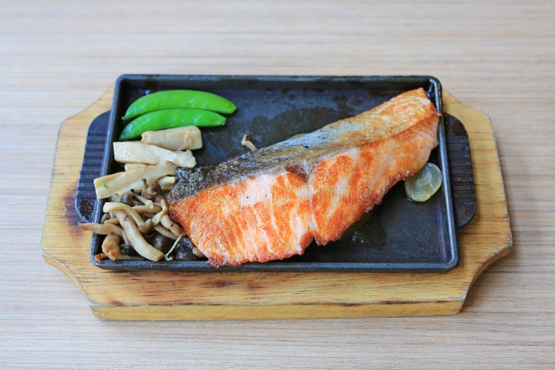 La bistecca di color salmone grigliata è servito con le verdure sulla piastra riscaldante Alimento giapponese di cucina immagine stock libera da diritti La bistecca di color salmone grigliata è servito con le verdure sulla piastra riscaldante Alimento giapponese di cucina immagine stock libera da diritti