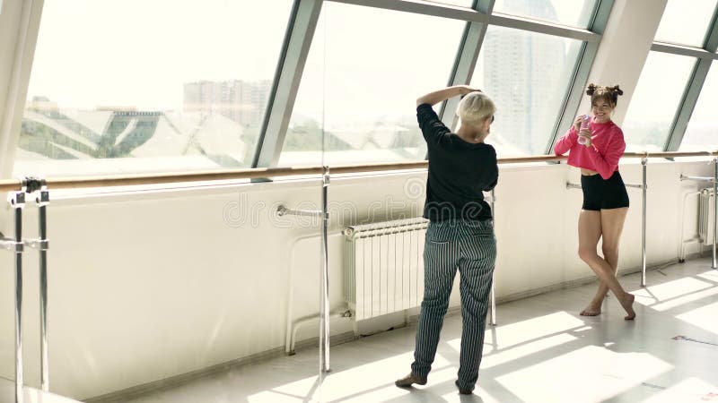 La blonde prend des photos d'une belle brune caucasienne dans une salle blanche