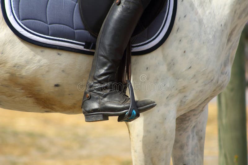 La bota negra del jinete en el estribo aprieta en el caballo, el pie en el estribo fotos de archivo libres de regalías La bota negra del jinete en el estribo aprieta en el caballo, el pie en el estribo fotos de archivo libres de regalías