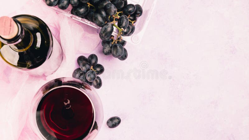 Alcohol and grapes on a violet and pink marble background. Alcohol and grapes on a violet and pink marble background.