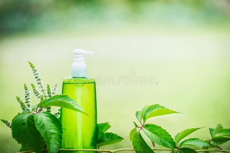 La bouteille cosmétique verte de produit pour la peau, le corps ou les soins capillaires avec le vert part au fond vert de nature photos stock La bouteille cosmétique verte de produit pour la peau, le corps ou les soins capillaires avec le vert part au fond vert de nature photos stock