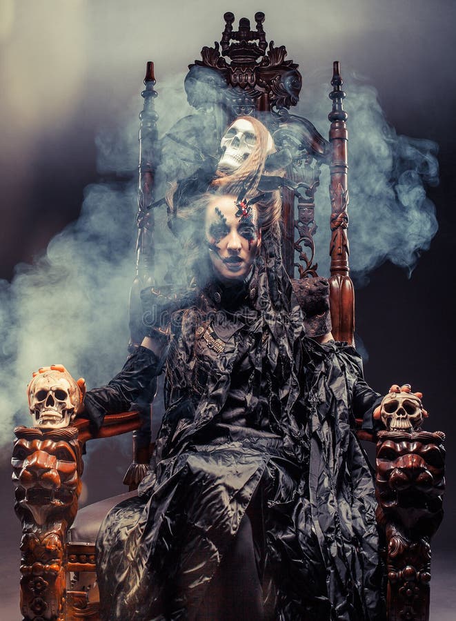 La bruja hermosa joven se sienta en una silla Brillante componga, cráneo, tema de Halloween del humo fotografía de archivo La bruja hermosa joven se sienta en una silla Brillante componga, cráneo, tema de Halloween del humo fotografía de archivo