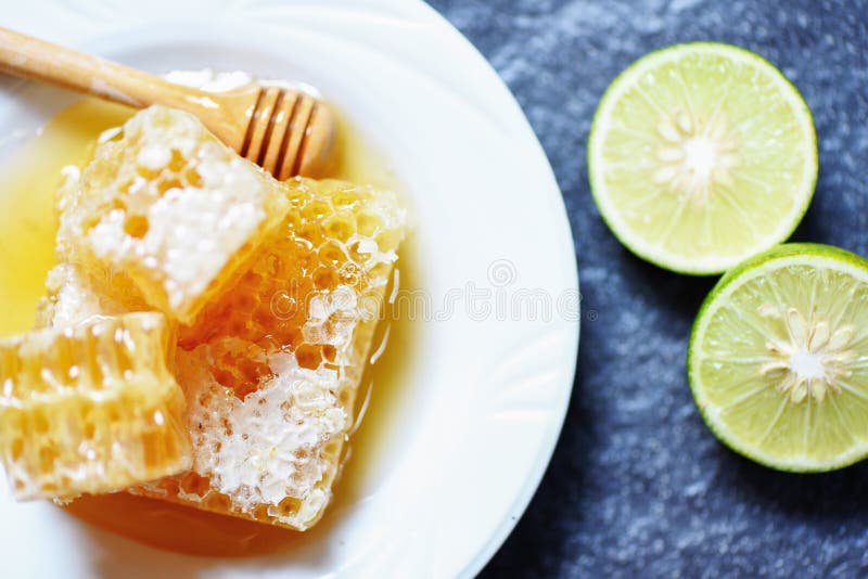 La calce fresca del limone e del miele/si chiude su della fetta dolce gialla del favo sul piatto bianco immagini stock La calce fresca del limone e del miele/si chiude su della fetta dolce gialla del favo sul piatto bianco immagini stock