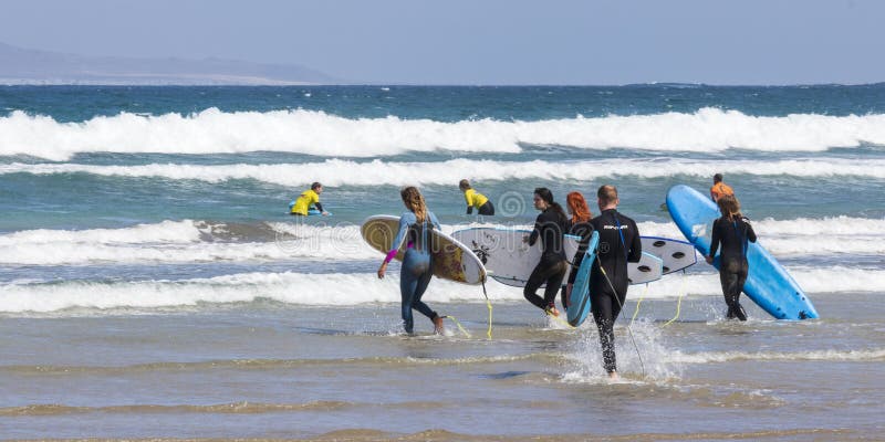 La Caleta, Spagna, 03-14-2019 Gruppo di surfista che cammina nelle onde alla spiaggia di Caleta della La Lanzarote Le Isole Canar immagine stock La Caleta, Spagna, 03-14-2019 Gruppo di surfista che cammina nelle onde alla spiaggia di Caleta della La Lanzarote Le Isole Canar immagine stock