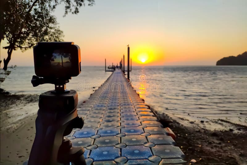 La caméra d'action a monté sur une photographie de trépied le pilier et le lever de soleil sur la plage images stock La caméra d'action a monté sur une photographie de trépied le pilier et le lever de soleil sur la plage images stock
