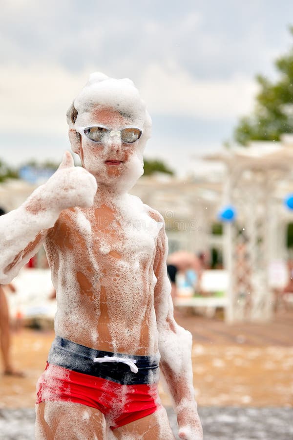 La cara de un niño con espuma, un niño apasionado y alegre en una fiesta de espuma en la que un niño está en la fiesta de espuma d fotos de archivo libres de regalías