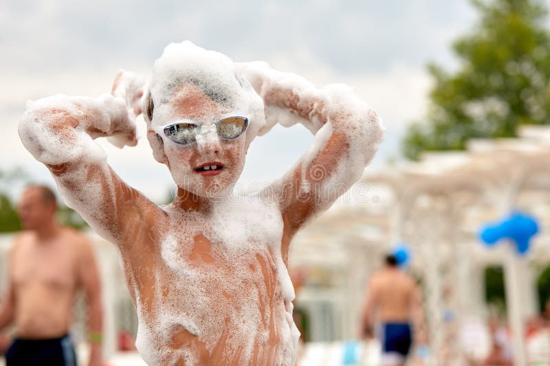La cara de un niño con espuma, un niño apasionado y alegre en una fiesta de espuma en la que un niño está en la fiesta de espuma d imagen de archivo