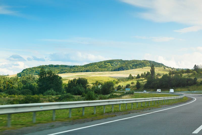 La carretera de asfalto vacía y el cielo azul con las nubes blancas en el día soleado Opinión clásica del panorama del camino a t imagen de archivo libre de regalías La carretera de asfalto vacía y el cielo azul con las nubes blancas en el día soleado Opinión clásica del panorama del camino a t imagen de archivo libre de regalías