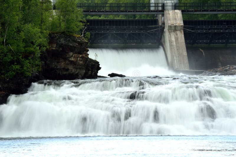 La cascada blanca masiva abajo oscila mientras que la central eléctrica de agua abre el muro de cemento fotos de archivo La cascada blanca masiva abajo oscila mientras que la central eléctrica de agua abre el muro de cemento fotos de archivo