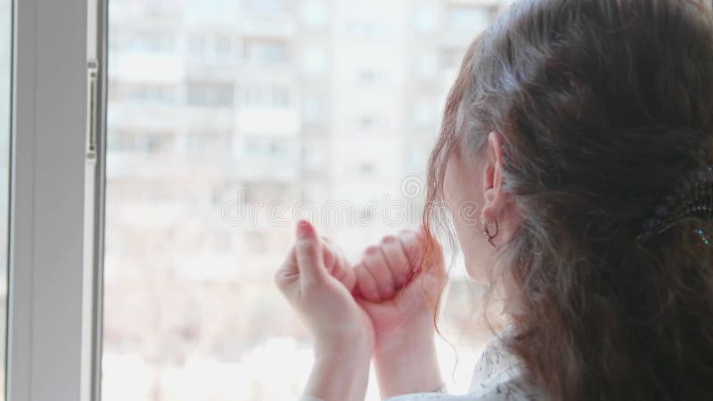 La chica con la máscara protectora está en el hospital. la niña se comunica a través de una ventana abierta y envía saludos y