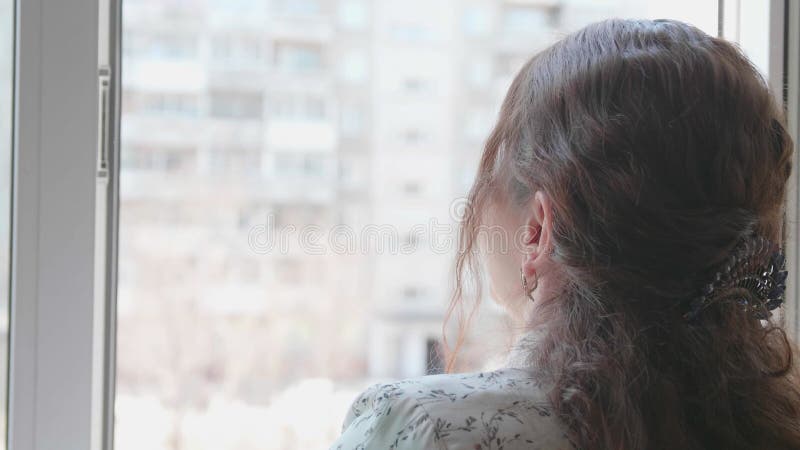 La chica con la máscara protectora está en el hospital. la niña se comunica a través de una ventana abierta y envía saludos y