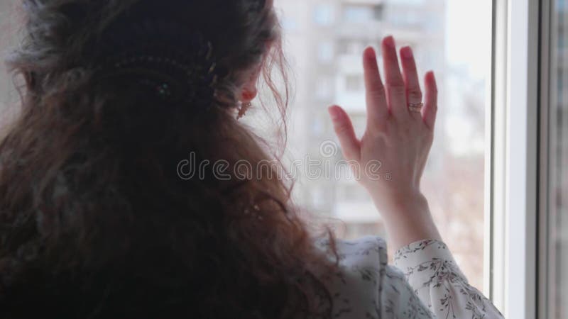 La chica con la máscara protectora está en el hospital. la niña se comunica a través de una ventana abierta y envía saludos y