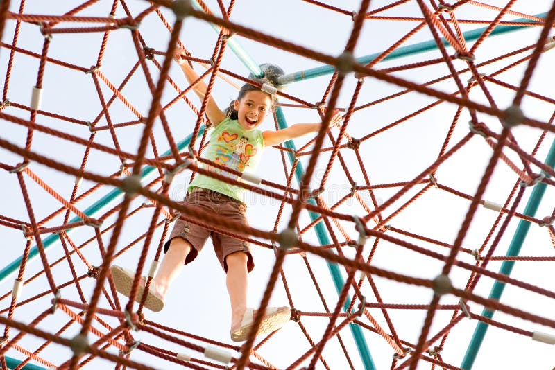 Young girl excited that she has reached the top of the giant climbing web activity. Young girl excited that she has reached the top of the giant climbing web activity.