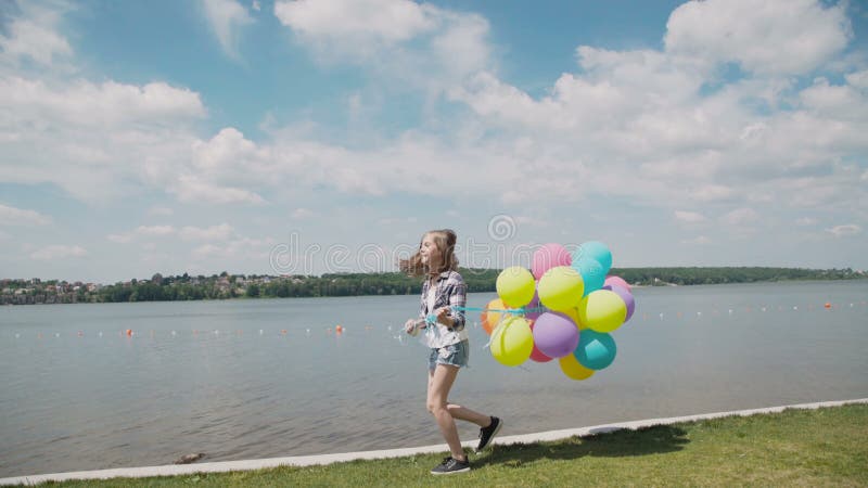 La chica joven bonita muestra emociones felices con los globos a disposición en el coustline almacen de video