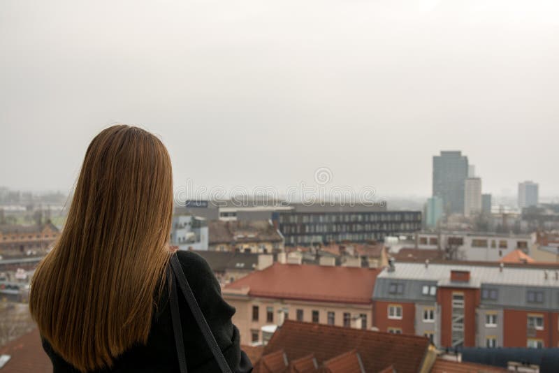 La chica joven con el abrigo de invierno está mirando en la ciudad imágenes de archivo libres de regalías La chica joven con el abrigo de invierno está mirando en la ciudad imágenes de archivo libres de regalías