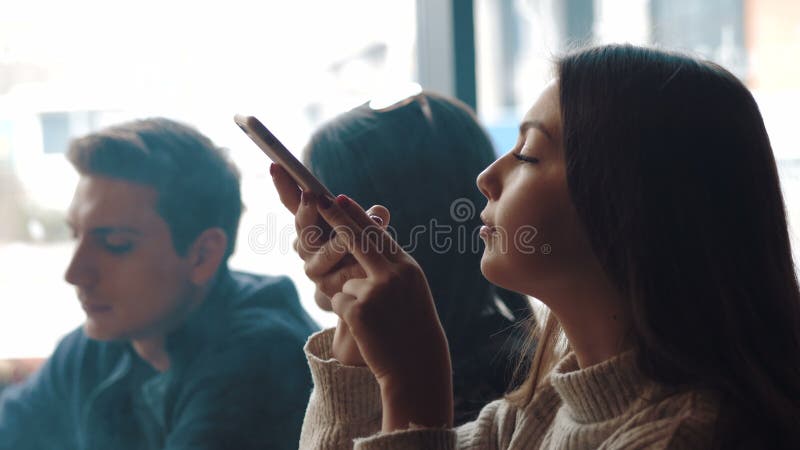 La chica joven está tomando imágenes de la comida Una compañía joven de la gente está fumando una cachimba y está comunicando en