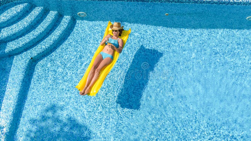 La chica joven hermosa que se relaja en la piscina, nadadas en el colch?n inflable y se divierte en agua el vacaciones de familia fotos de archivo La chica joven hermosa que se relaja en la piscina, nadadas en el colch?n inflable y se divierte en agua el vacaciones de familia fotos de archivo