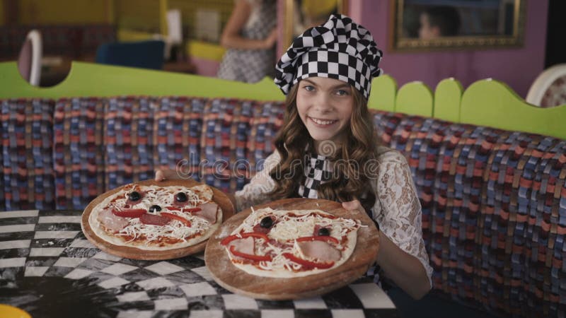 La chica joven muestra dos pizzas en la cámara 4K almacen de video