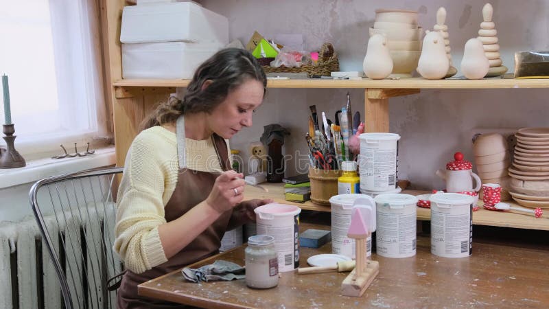 La chica maestro pinta juguetes de madera con pinturas acrílicas. producción de juguetes ecológicos para niños almacen de video