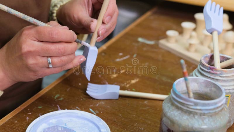 La chica maestro pinta juguetes de madera con pinturas acrílicas. producción de juguetes ecológicos para niños metrajes