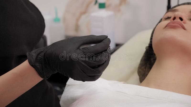La chiusura del cosmetologo estrae un ago sterile per una macchina per tatuaggi.