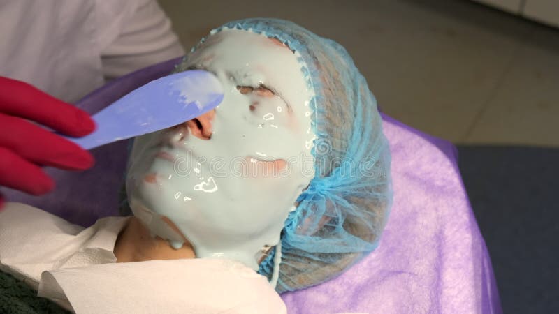 La chiusura di un estetista applica una maschera di alginato ad una giovane donna