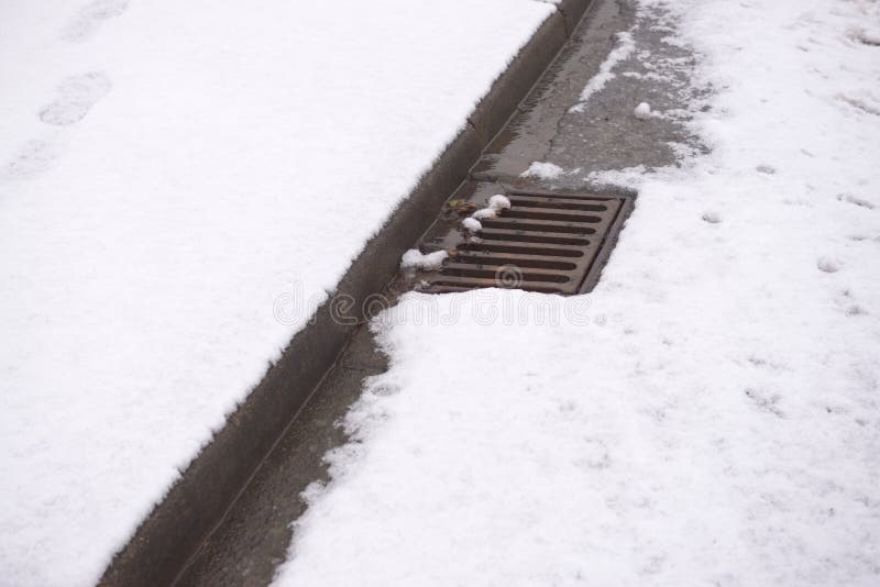 2 - Road covered in heavy snow with only the curbside drain showing. As the snow melts, the local area is at risk of flooding from all the water. 2 - Road covered in heavy snow with only the curbside drain showing. As the snow melts, the local area is at risk of flooding from all the water