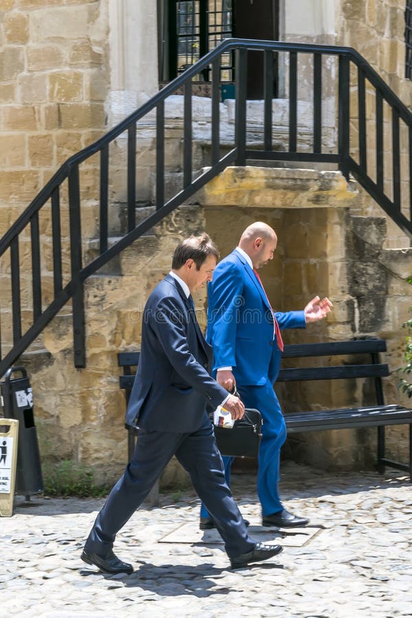 LA CHYPRE, NICOSIE - 10 JUIN 2019 : Deux hommes d'affaires habillés dans les costumes bleus marchant rapidement ou se dépêchant p photographie stock LA CHYPRE, NICOSIE - 10 JUIN 2019 : Deux hommes d'affaires habillés dans les costumes bleus marchant rapidement ou se dépêchant p photographie stock