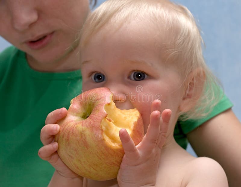 La chéri mignonne mange une pomme photo stock La chéri mignonne mange une pomme photo stock