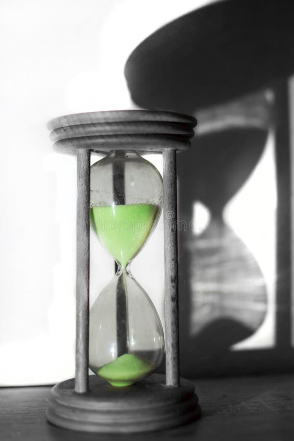 La clessidra dalla quale scorre la sabbia verde fotografia stock libera da diritti La clessidra dalla quale scorre la sabbia verde fotografia stock libera da diritti