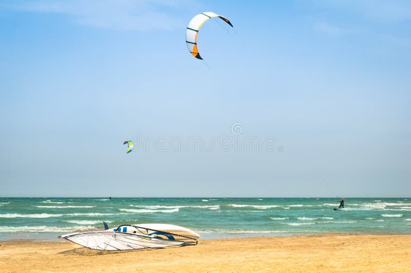 La cometa que practica surf en playa ventosa con windsurf tablero fotografía de archivo libre de regalías La cometa que practica surf en playa ventosa con windsurf tablero fotografía de archivo libre de regalías