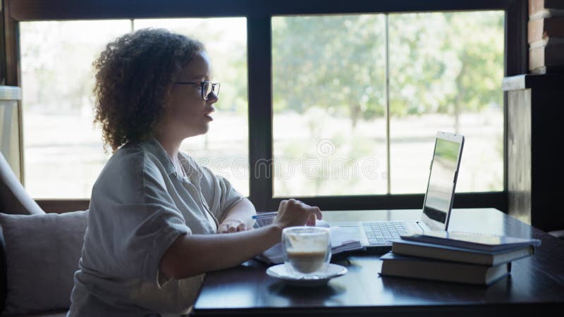 La communication en ligne, jeune femme subit la formation à distance à l'aide de la connexion vidéo sur l'ordinateur en café