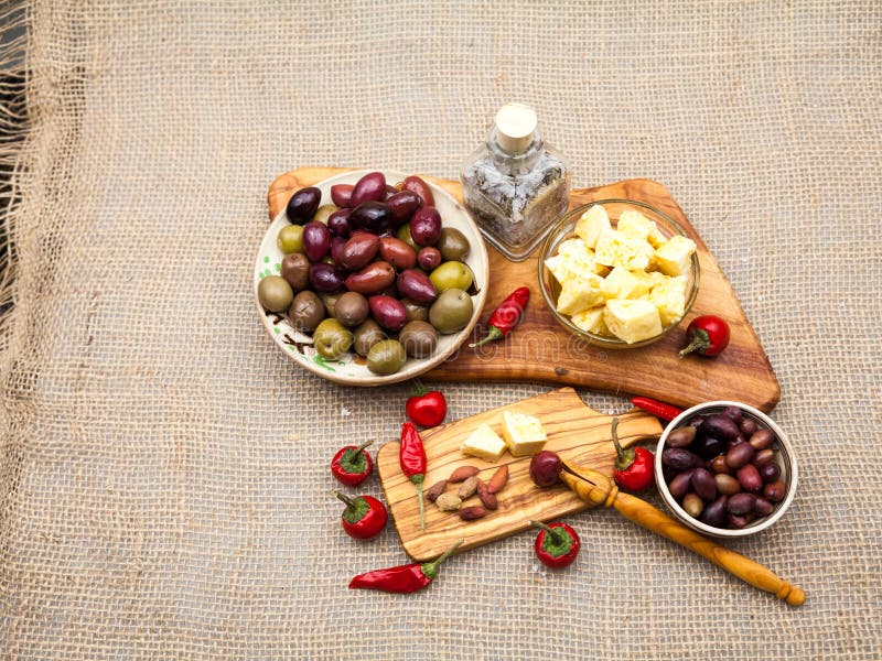 La composición con la madera verde oliva, aceitunas, queso junta las piezas en aceite, pan y especias de oliva fotografía de archivo La composición con la madera verde oliva, aceitunas, queso junta las piezas en aceite, pan y especias de oliva fotografía de archivo