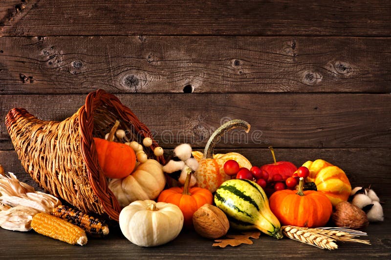 La cornucopie de Thanksgiving remplie de citrouilles d'automne et de légumes contre le bois foncé image libre de droits La cornucopie de Thanksgiving remplie de citrouilles d'automne et de légumes contre le bois foncé image libre de droits
