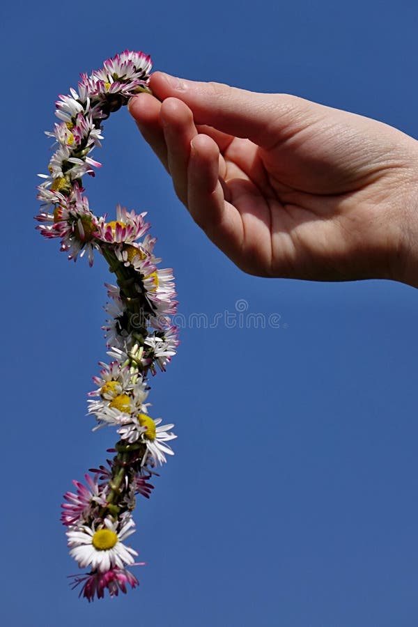La corona fatta delle margherite (Bellis Perrenis) ha tenuto in mano dell'adolescente contro cielo blu immagini stock La corona fatta delle margherite (Bellis Perrenis) ha tenuto in mano dell'adolescente contro cielo blu immagini stock