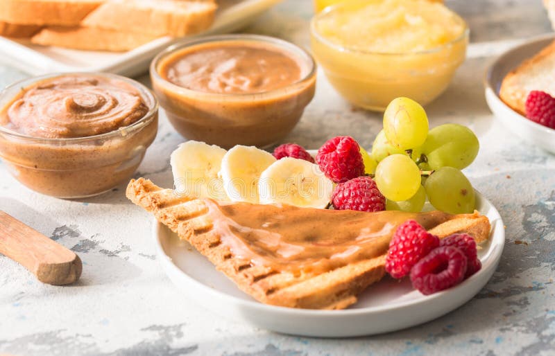La data del cioccolato della nocciola ha sparso il burro di dado ed il pane tostato del pane sul piatto bianco Diffusione assorti immagini stock libere da diritti La data del cioccolato della nocciola ha sparso il burro di dado ed il pane tostato del pane sul piatto bianco Diffusione assorti immagini stock libere da diritti