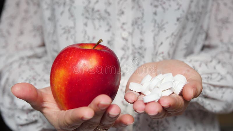 La doctora lleva una pastilla en una mano y una manzana en la otra. ofrecer una elección en favor de una nutrición adecuada y