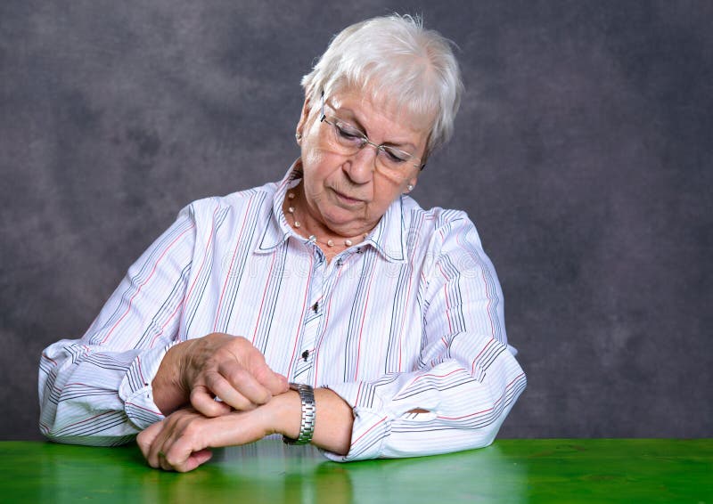 La donna anziana pelosa grigia ha messo il suo orologio immagine stock