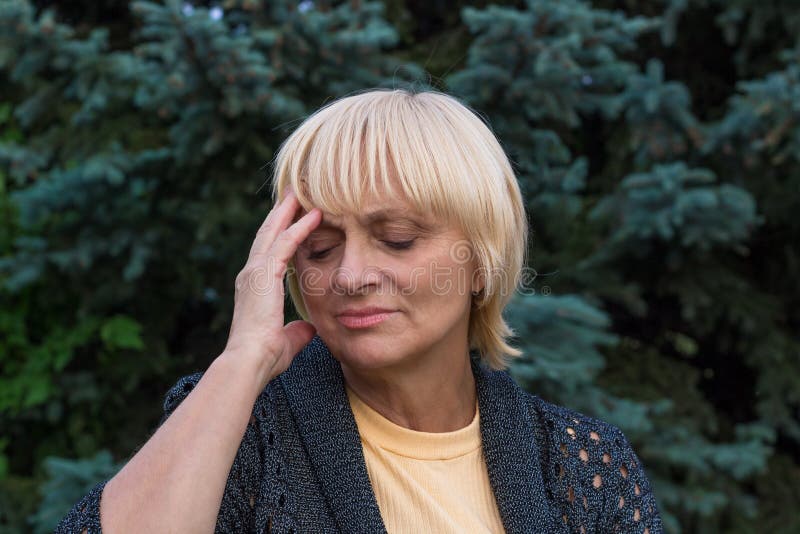 La donna anziana sta avendo un'emicrania e sta toccando la sua testa fotografie stock La donna anziana sta avendo un'emicrania e sta toccando la sua testa fotografie stock