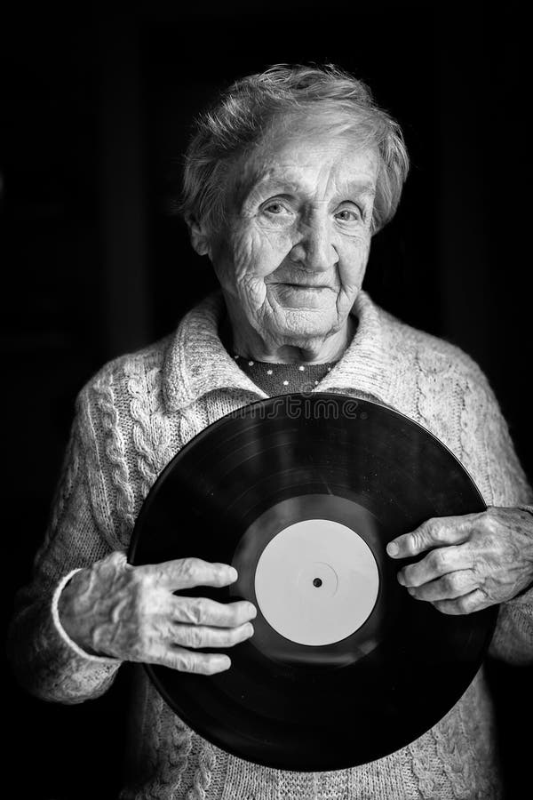 La donna anziana sta tenendo un'annotazione di vinile fotografie stock La donna anziana sta tenendo un'annotazione di vinile fotografie stock