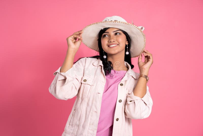 La donna asiatica con il cappello dell'estate gode di di ballare contro il rosa fotografie stock La donna asiatica con il cappello dell'estate gode di di ballare contro il rosa fotografie stock