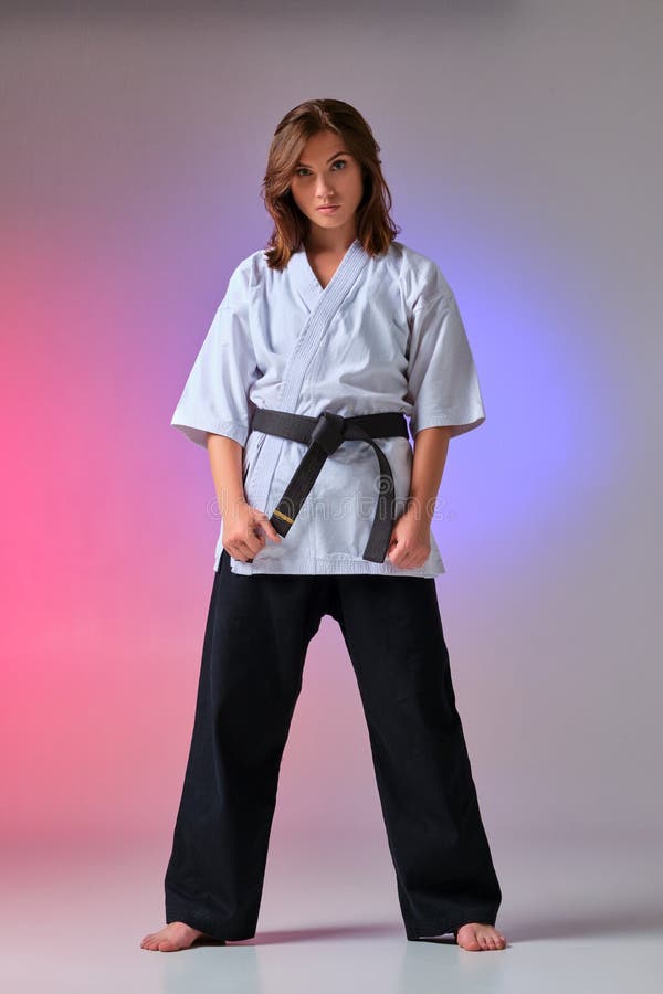 La donna atletica in kimono tradizionale sta praticando il karatè in studio fotografie stock libere da diritti La donna atletica in kimono tradizionale sta praticando il karatè in studio fotografie stock libere da diritti