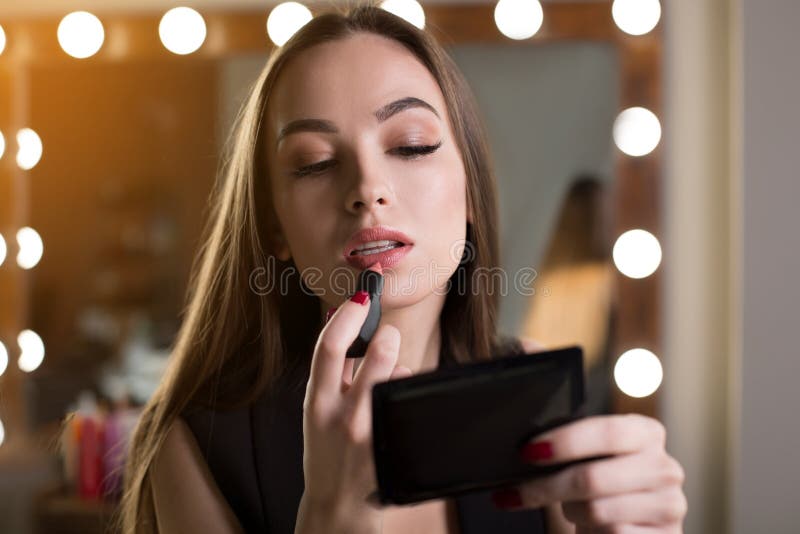 La donna attraente sta facendo il trucco del giorno immagine stock La donna attraente sta facendo il trucco del giorno immagine stock