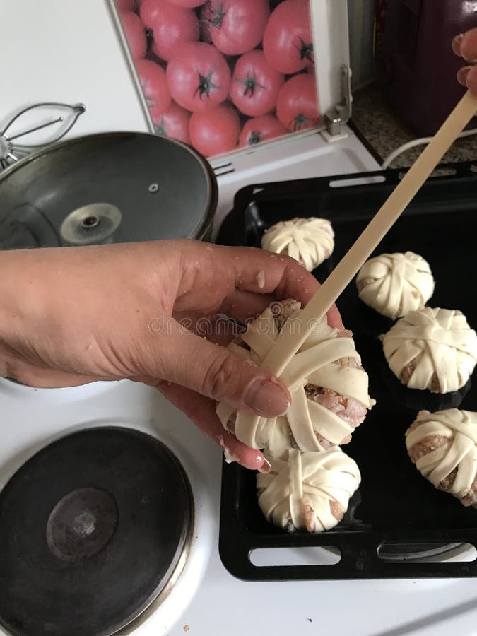 La donna avvolge le palle di carne tritata nelle strisce della pasta sfoglia Mazzi di carne tritata e di pasta fotografia stock La donna avvolge le palle di carne tritata nelle strisce della pasta sfoglia Mazzi di carne tritata e di pasta fotografia stock
